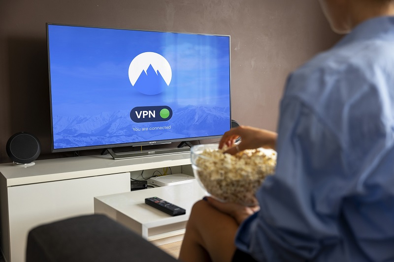 Ein Mann mit Popcorn blickt auf einen Fernseher mit VPN-Verbindung